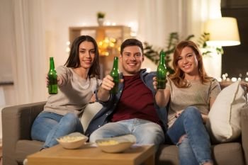 friendship and leisure concept - happy friends toasting non-alcoholic beer at home in evening. friends toasting non-alcoholic beer at home