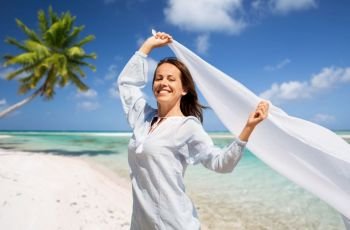 people and leisure concept - happy woman with shawl waving in wind over tropical beach background in french polynesia. happy woman with shawl waving in wind on beach