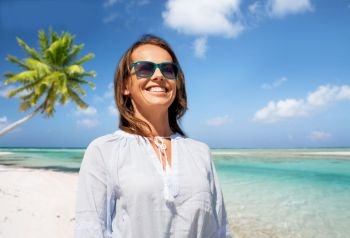 people and leisure concept - happy smiling woman in sunglasses over tropical beach background in french polynesia. happy smiling woman in sunglasses over beach