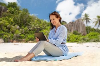 technology, people and leisure concept - happy smiling woman with tablet pc computer over tropical beach on seychelles island background. happy smiling woman with tablet pc on summer beach