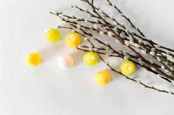 holidays and object concept - pussy willow branches and easter egg candles on white background. pussy willow branches and easter egg candles