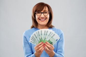 savings, finances and people concept - smiling senior woman holding hundred euro money banknotes. senior woman with hundreds of euro money banknotes