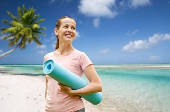 fitness, sport and healthy lifestyle concept - happy smiling woman with exercise mat over tropical beach background in french polynesia. happy smiling woman with exercise mat over beach