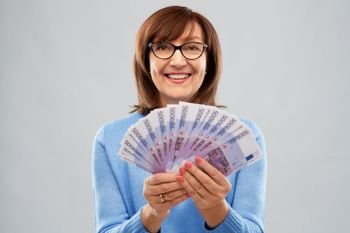 savings, finances and people concept - smiling senior woman holding five hundred euro money banknotes. senior woman holding hundred euro money banknotes