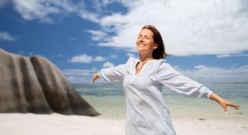 people and summer concept - happy smiling woman enjoying sun over seychelles island tropical beach background. happy woman over seychelles island tropical beach