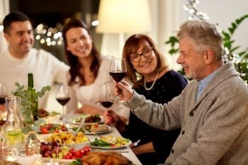 celebration, holidays and people concept - happy grandfather with glass of red wine toasting with family having dinner party at home. happy family having dinner party at home