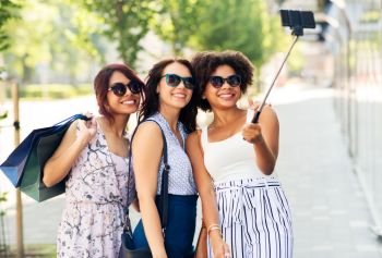 sale, friendship and technology concept - happy young women with shopping bags taking selfie by smartphone in outdoors. women with shopping bags taking selfie outdoors