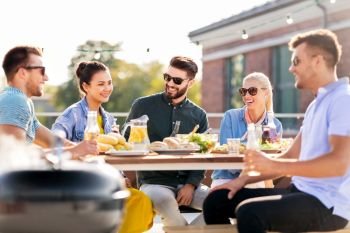 leisure and people concept - happy friends having barbecue party on rooftop in summer. happy friends having bbq party on rooftop