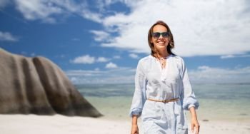 people and summer concept - happy smiling woman walking along over seychelles island tropical beach background. happy woman over seychelles island tropical beach
