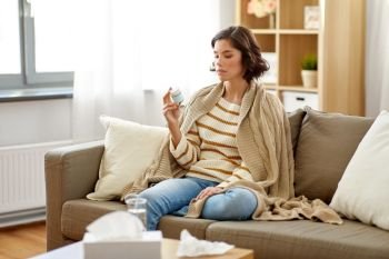 people, health and medicine concept - sad sick woman in blanket with drug at home. sad sick woman in blanket with drug at home