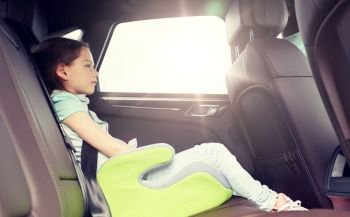 family, transport, road trip and people concept - happy little girl in safety seat driving in car. family with child in safety seat driving car