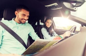 leisure, road trip, travel and people concept - happy man and woman driving in car and searching location on map. happy man and woman with road map driving in car