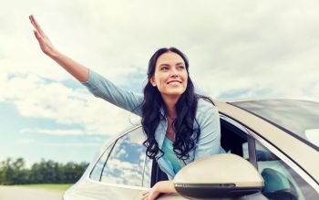 summer vacation, holidays, travel, road trip and people concept - happy young woman driving in car and waving hand. happy young woman driving in car and waving hand