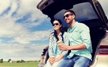 travel, summer vacation, road trip, leisure and people concept - happy couple drinking coffee from disposable cups sitting on trunk of hatchback car outdoors. happy couple with coffee at hatchback car trunk