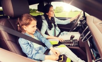 family, transport, road trip and people concept - happy woman with little daughter driving in car. happy woman with little child driving in car