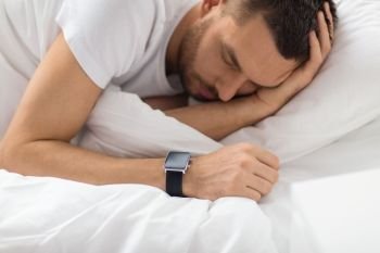 people, technology and rest concept - close up of man with smart watch sleeping in bed. close up of man with smart watch sleeping in bed