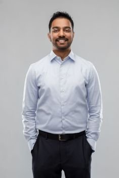 business, office worker and people concept - smiling indian businessman in shirt over grey background. indian businessman in shirt over grey background
