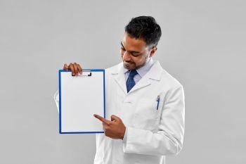 medicine, science and profession concept - smiling indian male doctor or scientist in white coat with blank paper on clipboard over grey background. doctor or scientist with white paper on clipboard