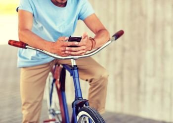 people, communication, technology, leisure and lifestyle - close up of man texting on smartphone with fixed gear bike on city street. close up of man with smartphone and bike on street