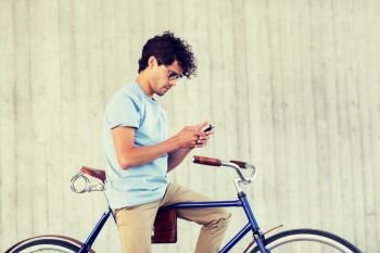 people, communication, technology, leisure and lifestyle - hipster man texting on smartphone with fixed gear bike on city street. man with smartphone and fixed gear bike on street