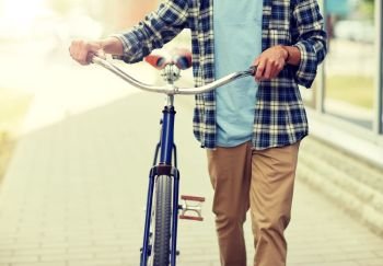people, style and lifestyle concept - close up of young man with fixed gear bicycle walking along city street. close up of man with bicycle walking along city
