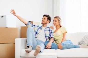 moving, people, repair and real estate concept - happy couple with big cardboard boxes on sofa at new home. happy couple with cardboard boxes at new home