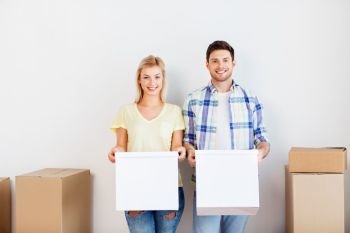 mortgage, moving, people and real estate concept - happy couple with cardboard boxes at new home. happy couple with boxes moving to new home