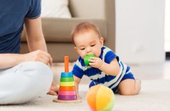 family, fatherhood and childhood concept - happy baby boy with father and toy pyramid at home. baby boy with father and pyramid toy at home