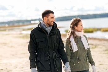 love, relationship and people concept - happy couple at autumn beach holding hands. happy couple at autumn beach holding hands