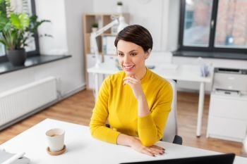 business and people concept - happy businesswoman sitting at office table. happy businesswoman sitting at office table
