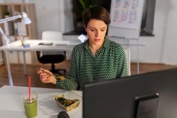 business, overwork, deadline and people concept - businesswoman with computer eating salad at night office. businesswoman eating and working at night office