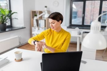 business, technology and time management concept - happy smiling businesswoman using smart watch at office. happy businesswoman using smart watch at office