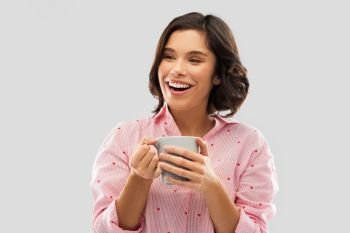 people and bedtime concept - happy young woman in pajama with mug of coffee. happy young woman in pajama with mug of coffee