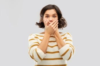 emotion, expression and people concept - shocked young woman in striped pullover covering her mouth by hands over grey background. shocked young woman covering her mouth by hands