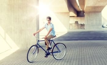people, style, leisure and lifestyle - young hipster man riding fixed gear bike on city street. young hipster man riding fixed gear bike