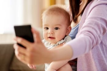 family and motherhood concept - close up of mother with little baby son taking selfie by smartphone at home. close up of mother with baby taking selfie