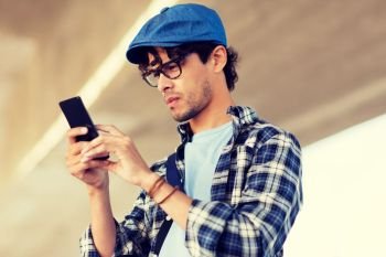 leisure, technology, communication and people concept - hipster man texting message on smartphone or playing augmented reality game. hipster man texting message on smartphone
