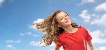people concept - smiling teenage girl in red t-shirt with long hair waving over blue sky and clouds background. smiling teenage girl in red with long wavy hair