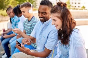 technology, friendship and international concept - group of students or friends with smartphones in city. friends with smartphones and tablet pc in city