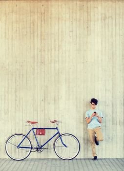 people, communication, technology, leisure and lifestyle - hipster man with smartphone and fixed gear bike on city street. man with smartphone and fixed gear bike on street