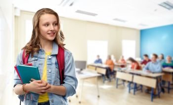 education, school and people concept - happy smiling teenage student girl with bag and books over classroom background. happy smiling teenage student girl with school bag