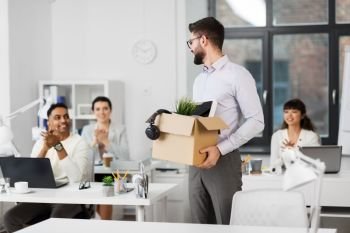 business, new job and quit concept - happy smiling office workers applauding to male colleague with box of personal stuff. office workers applauding to male colleague
