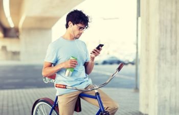 people, communication, technology and lifestyle - hipster man with smartphone, earphones and thermos cup on fixed gear bike listening to music on city street. man with smartphone and earphones on bicycle