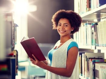 education, high school, university, learning and people concept - happy smiling african american student girl reading book at library. happy african student girl reading book at library