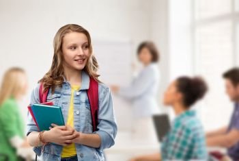 education, school and people concept - happy smiling teenage student girl with bag and books over classroom background. happy smiling teenage student girl with school bag