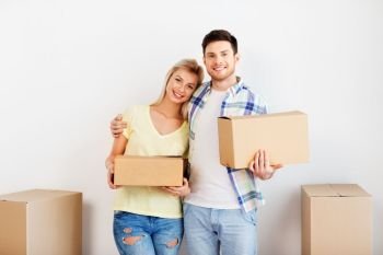 mortgage, moving, people and real estate concept - happy couple with big cardboard boxes at new home. happy couple with boxes moving to new home