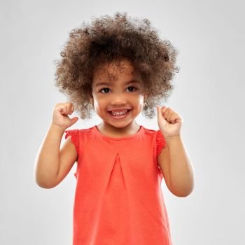 childhood and people concept - happy little african american girl over grey background. happy little african american girl over grey