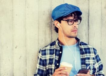 people, technology, leisure and lifestyle - man with earphones and smartphone drinking coffee and listening to music on city street. man with earphones and smartphone drinking coffee