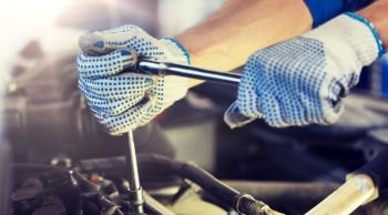 car service, repair, maintenance and people concept - auto mechanic man with wrench and lamp working at workshop. mechanic man with wrench repairing car at workshop