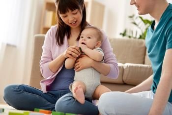 mixed-race family, parenthood and people concept - happy mother, father and baby boy playing toy blocks at home. happy family with baby boy playing at home